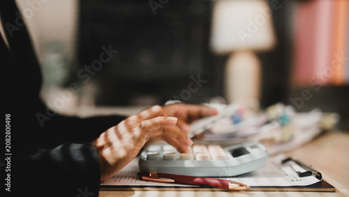 Fotografie Hands press keys on a calculator at a desk