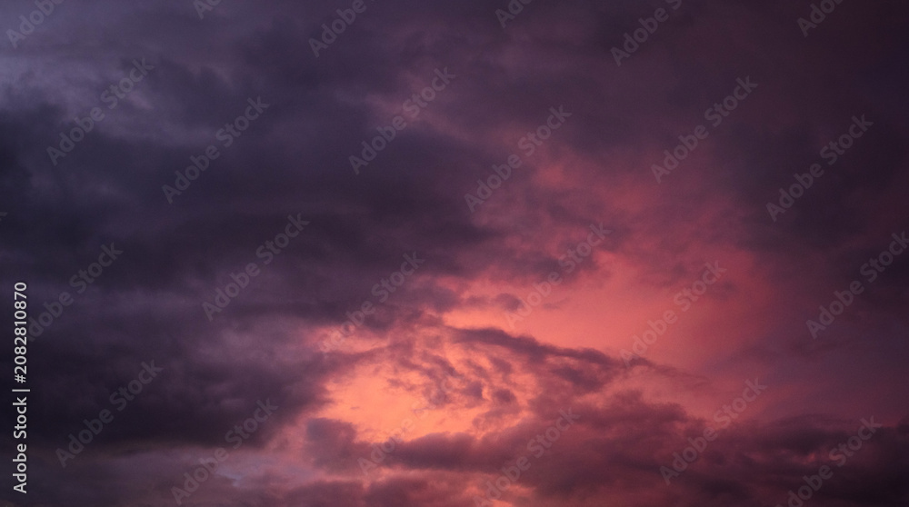 Obraz premium Dramatic sunset over a dark landscape with fiery clouds, atmospheric sky view, moody natural scenery, intense color contrast, evening atmosphere