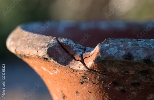 close up of cracked terracotta pot rim earthy orange tones natural outdoor light aged texture