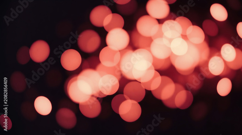 Soft pink glowing bokeh light circles and delicate sparkle particles floating dreamily against a pure solid black background.