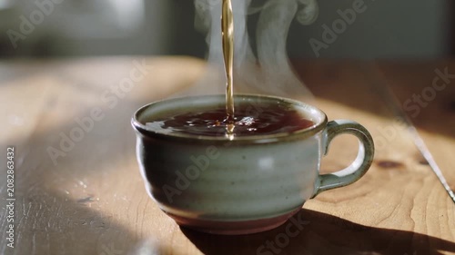 Pouring hot tea into a ceramic cup in morning sunlight