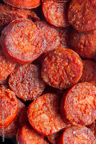 Spicy traditional sliced fried Spanish chorizo sausage background backdrop. Traditional Spanish food concept.
