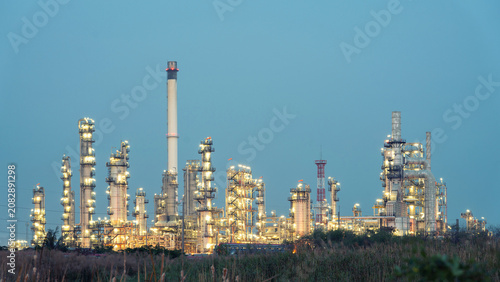 Tableau sur toile Industrial Landscape at Dusk: A sprawling industrial complex, illuminated by countless lights, stands silhouetted against the twilight sky, representing the power and scale of modern industry