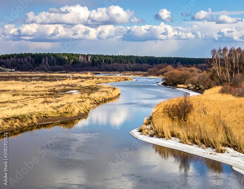 Peaceful river flowing through dry grassland under cloudy sky