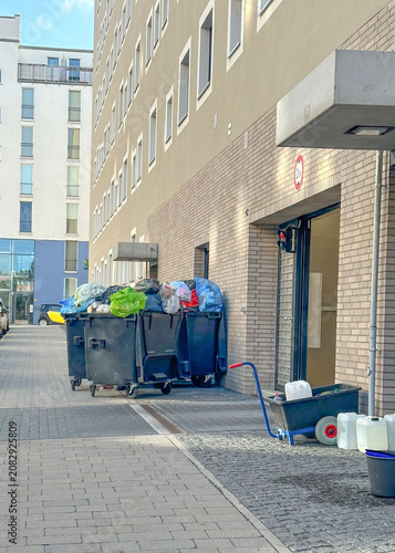 Overflowing trash containers outside an apartment building


