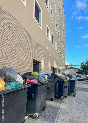 Overflowing trash containers outside an apartment 
