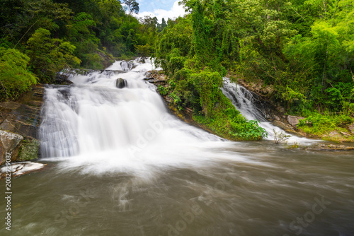 Schilderij op canvas Amazing double streams of Khlong Nam Lai waterfall rushing into a natural pool, surrounded by vibrant green tropical jungle in Khlong Lan National Park, Kamphaeng Phet, Thailand