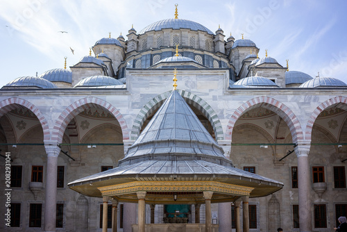 Foto The courtyard of a grand Ottoman mosque in Istanbul features an ornate ablution fountain surrounded by arched colonnades with red-and-white striped marble archways