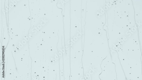 Soft raindrops streaming down window glass, pale blue background, minimal texture and calm mood.