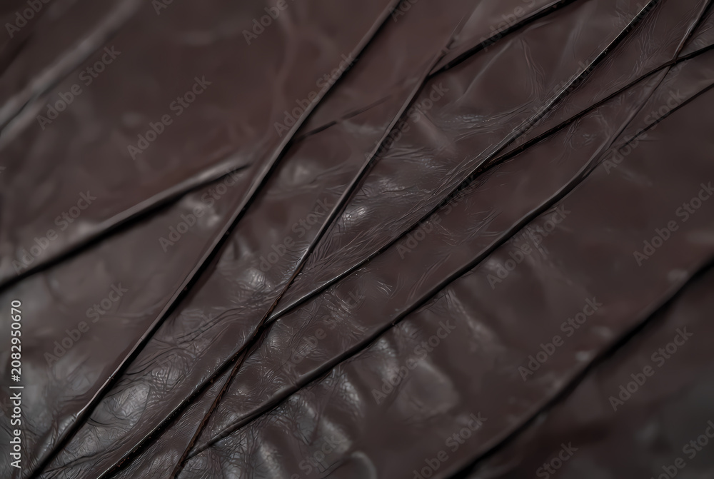 Obraz premium A close-up view of a dark brown leather texture with deep creases and folds