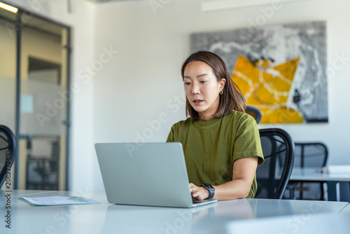 Fotografie Asian businesswoman working on laptop in modern office
