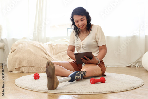 Obraz na płótnie Cheerful Asian woman with prosthetic leg hold digital tablet, surfing on internet