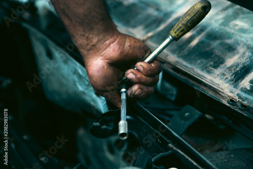 Auto mechanic working in auto repair service. Close-up of hand with screwdriver