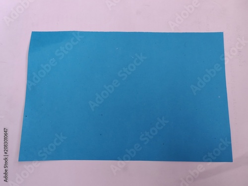 Konstfotografi A blue rectangular object is placed on a light purple surface indoors