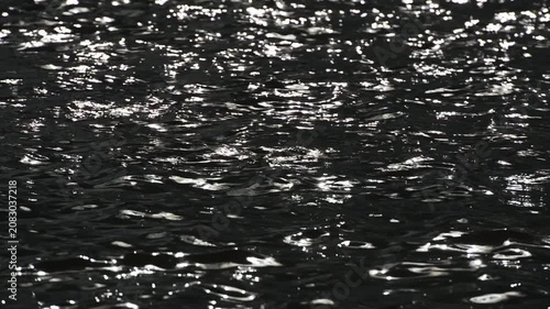 Shining sun flares playing on rippling surface of ocean water waves.