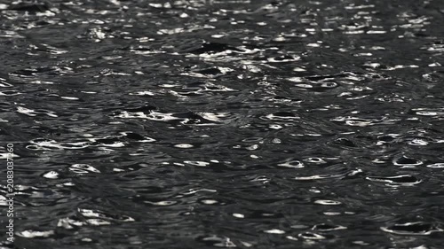 Shining sun flares playing on rippling surface of ocean water waves.