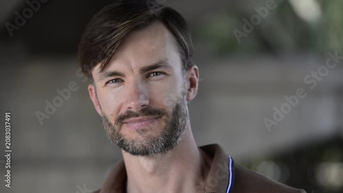 Handsome bearded man turning around, looking at camera and smiling.