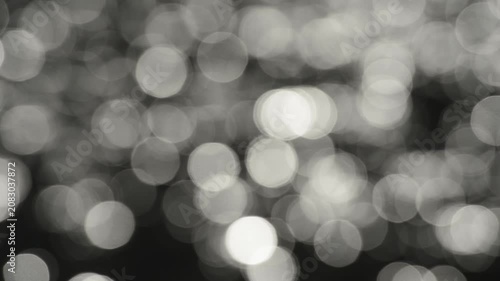 Bokeh of sun flares on water waves with camera moving from close up to wide shot.
