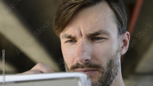Handsome bearded man looking and sketching in paper notebook close up.