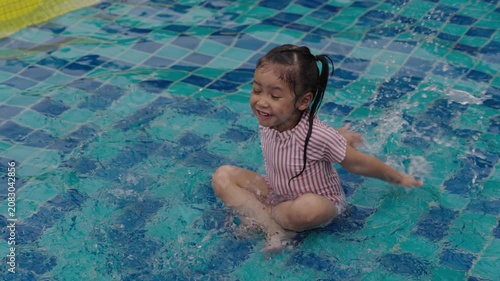 slow motion of happy preschool child girl playing water splashing in swimming pool