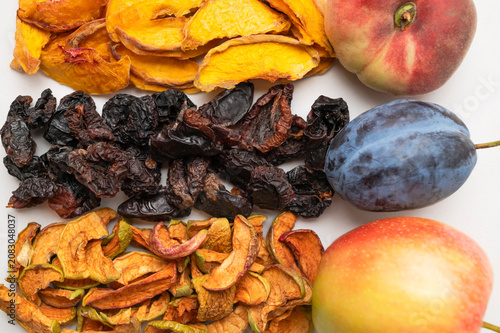Fresh peach, plum, apple with matching dried fruits arranged in top view on light background. Fresh produce highlights healthy nutrition, wholesome ingredients, food branding and educational content.