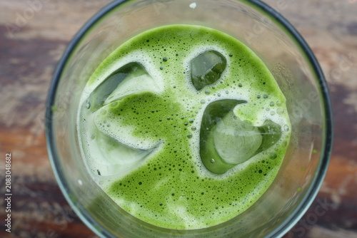 Tableau sur toile Vibrant Green Elixir: A refreshing, ice-cold green drink, likely a matcha or herbal smoothie, sits in a clear glass, its foamy surface hinting at a healthy and invigorating beverage