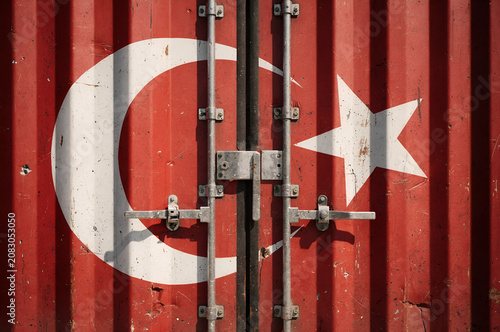 Close up detail of a red corrugated shipping container painted with the national flag of turkey showing metal locking bars