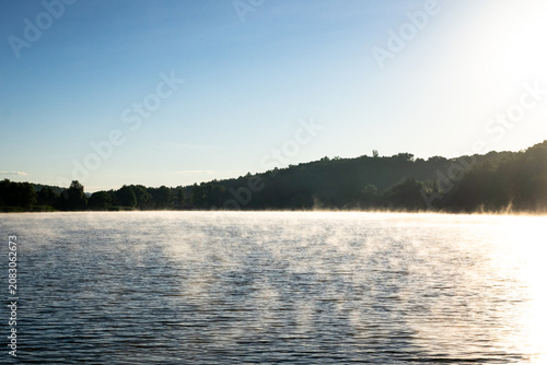 Cuadro en lienzo Mist trails in ribbons across the lake as sunrise brightens a clear sky