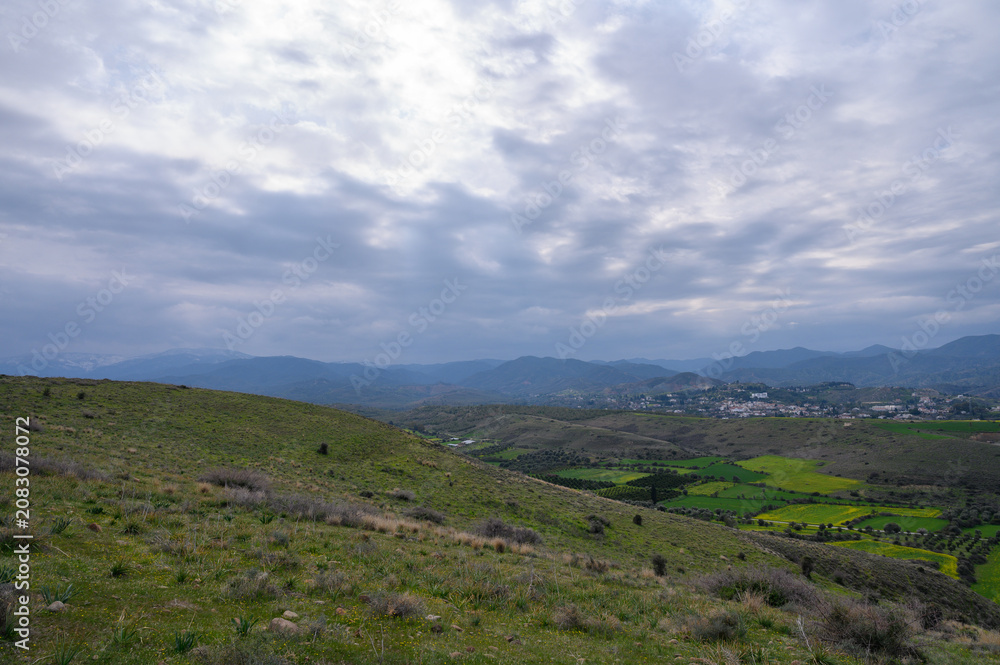 Obraz premium Rolling green hills and dramatic clouds create a serene landscape in a rural