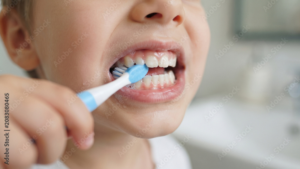 Fototapeta premium Extreme close-up of a child's teeth being brushed with a toothbrush, dental health and oral hygiene concept, clean mouth self-care routine