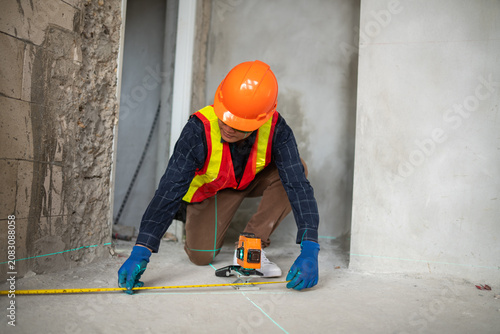 Construction professional using a laser level to measure the floor at a renovation site