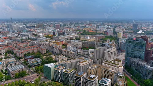 Aerial drone view of Potsdamer Platz high-rise towers, surrounding office blocks, and the Berlin cityscape extending to the horizon in Berlin, Germany, summer.