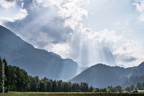 Schilderij op canvas Stunning Crepuscular Rays over Alpine Mountain Landscape, Sunbeams Breaking thro