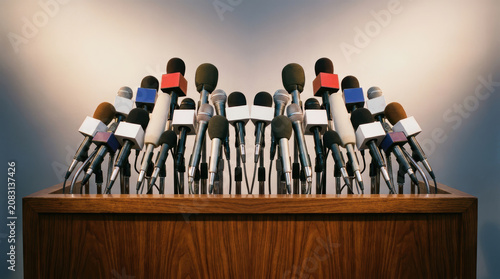 Multiple microphones on wooden podium ready for press conference or public speech with neutral background and lighting