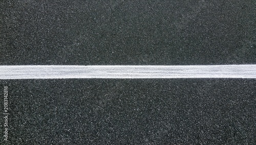 A stark white line divides a textured dark gray asphalt surface