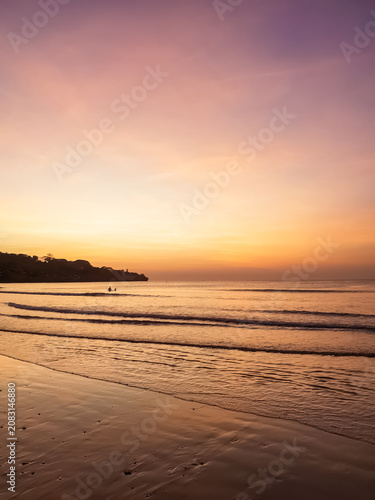 Foto Tropical beach at sunset with orange and purple sky reflecting on wet sand, silh