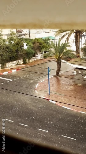 Hailstones falling on urban street with palm trees