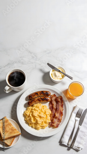 Flat lay of classic American breakfast with scrambled eggs, bacon, and sausages.
