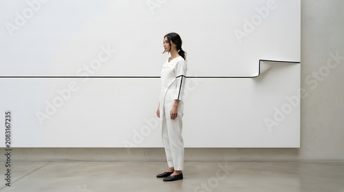 A Young Woman Standing Profile Against a Minimalist White Gallery Wall Featuring Modern Architectural Lines and Interior Design Aesthetics