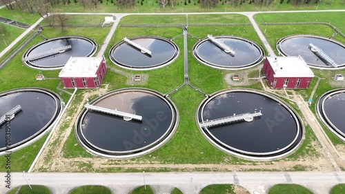 Aerial view of municipal wastewater treatment plant showing multiple circular tanks, filtration systems, and surrounding green areas, highlighting the infrastructure and operational layout of the faci