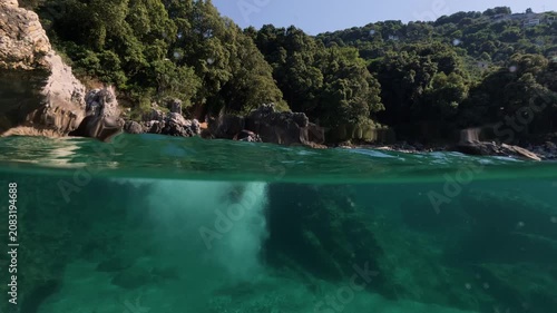 Boy jumping into sea water split shot over under half underwater view