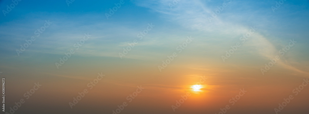 Fototapeta premium Golden sunset glowing beneath a blue sky with soft clouds and warm evening light.