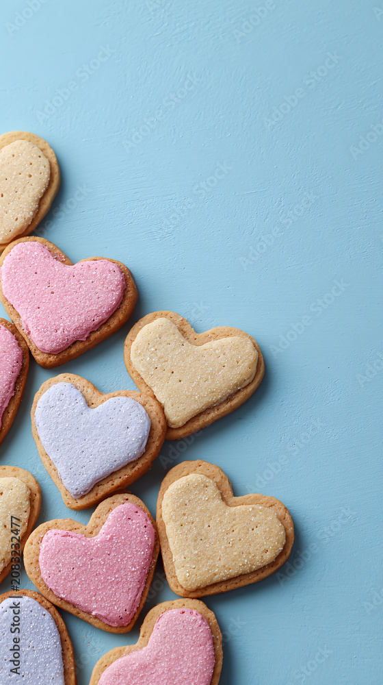 Obraz premium Heart-Shaped Cookies with Pink, Purple, and Cream Icing on Light Blue Background