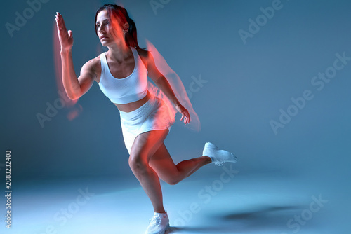 female athlete running in studio with blue background, dynamic and energetic side view, white sports bra, white skirt, white sneakers, fabric and textile materials, fitness and sports.