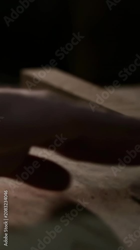 Vertical video: Touching bare toe signaling hand dark sleeve nudging block on dusty bench sawdust
