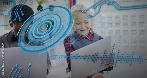 Interacting students in collared and red plaid using laptop and tablet with blue HUD in classroom