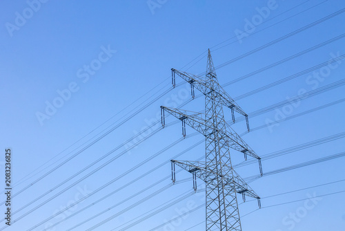 Strommast mit Hochspannungsleitungen vor blauem Himmel