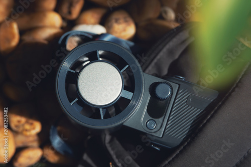Top view of a modern portable mini fan tucked inside a black bag on a natural brown stone background