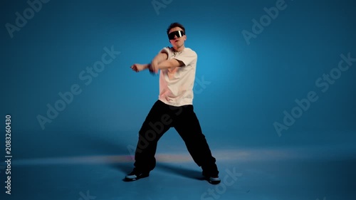 Hip hop dancer performs dynamic freestyle move against blue studio background