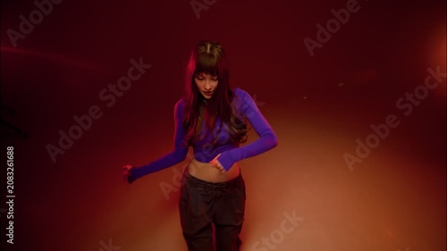 Contemporary dancer holds raised arms in dramatic red studio glow, striking modern pose low key mood